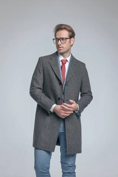 彼の手のひらをこすりセクシーなファッションモデル 離れて見て 素敵なコートと眼鏡を身に着けている — ストック写真