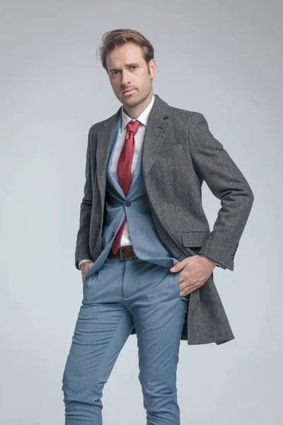性感时尚模特穿着外套 双手插在灰色背景的口袋里 — 图库照片