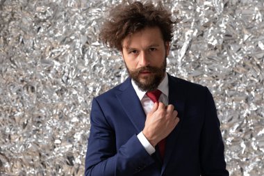 Yakışıklı iş adamı kravatını düzeltiyor ve Staniol 'ün arka planında kameraya bakıyor.