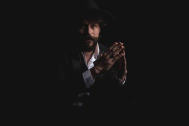 Kameraya bakıp şapka takarken el ele tutuşan manken.