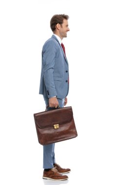 Mavi takım elbiseli, gülümseyen ve stüdyoda beyaz arka planda sırada bekleyen zarif genç adamın yan görüntüsü.