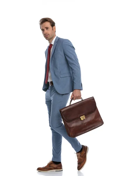 穿着蓝色西服的性感优雅商人侧看 提着包 走在工作室的白色背景前 — 图库照片