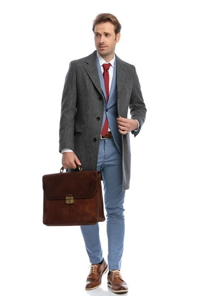 有魅力的商人 身穿手提箱调整外套 侧身观望 在工作室的白色背景上独立行走 — 图库照片