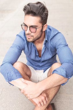 kaldırımda oturan adam ve onun tarafına bakar