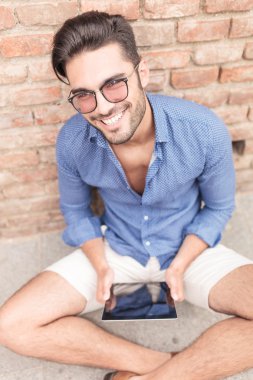 tablet bilgisayarda çalışan genç adam gülümsüyor