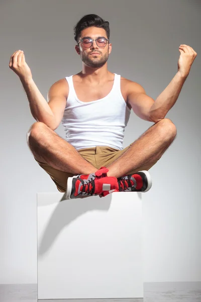 Hombre en forma sentado y meditando en un cubo — Foto de Stock