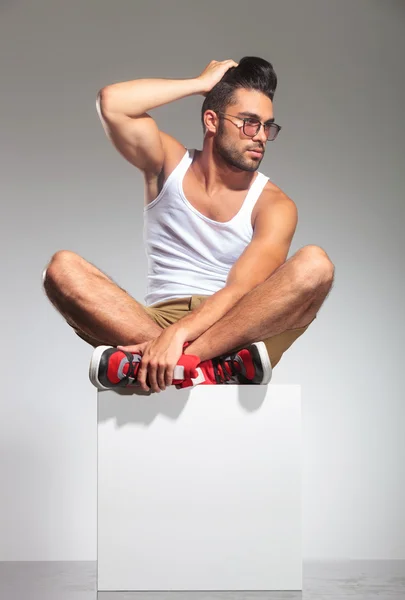 Man in yoga position on  cube with hand on head — Stock Photo, Image