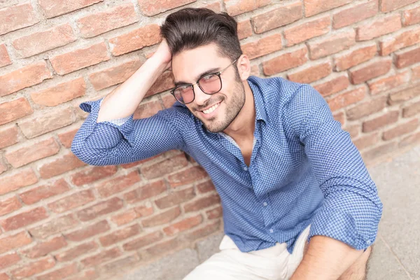 Man with glasses fixing his hair while seated — Stock Photo, Image