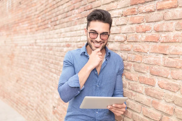 Sorrindo homem pensativo lendo em um computador tablet — Fotografia de Stock