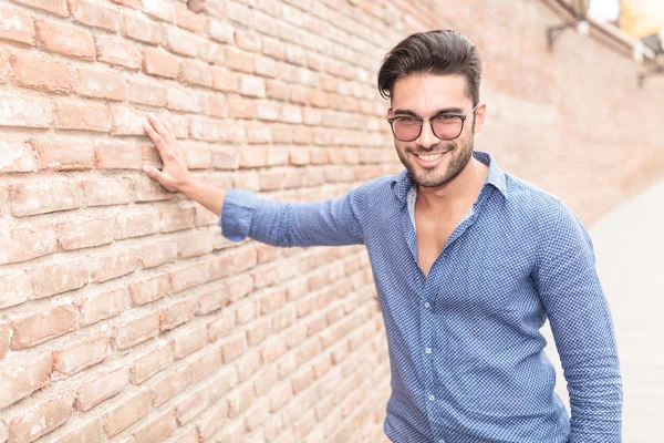 Uomo casual sta con mano sul muro di mattoni — Foto Stock