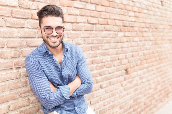 Casual man resting near brick wall with hands crossed — Stock Photo, Image
