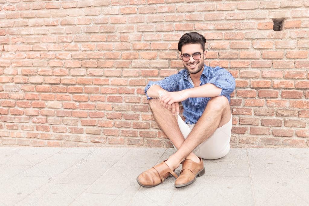  man sitting near brick wall and smiles
