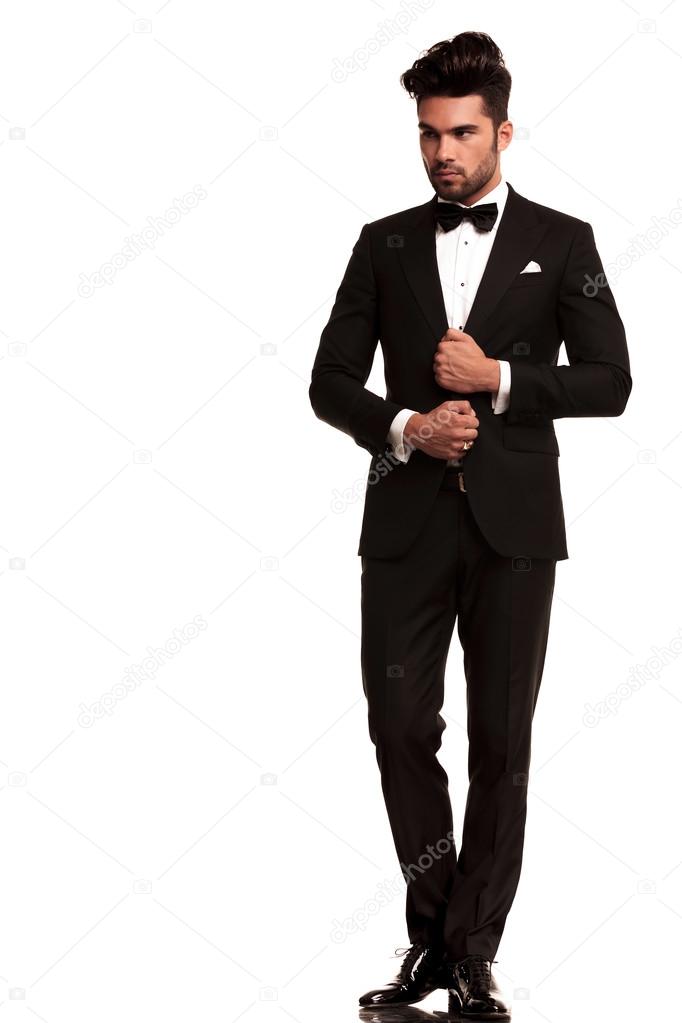 Elegant young fashion man adjusting his tuxedo