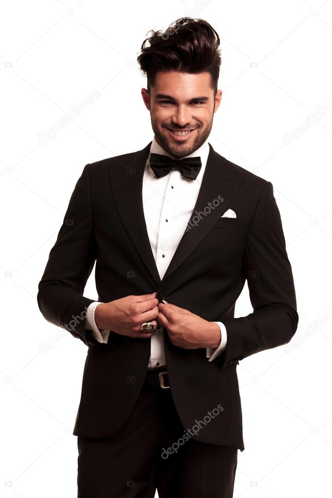 happy young elegant man in tuxedo buttoning his coat