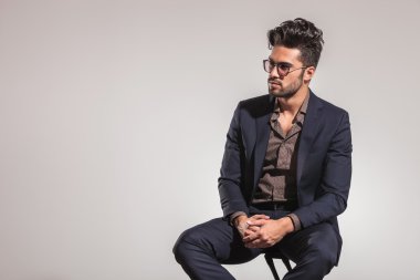 takım elbise içinde oturan genç adam onun tarafına bakar 