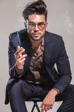 moda erkek takım elbise ve sigara ve oturan gözlük