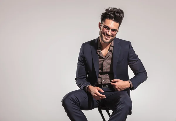 Smart casual man in pak zittend op een stoel en lachen — Stockfoto