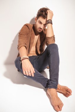 Bacaklarını çapraz katta oturan üzgün bir adam