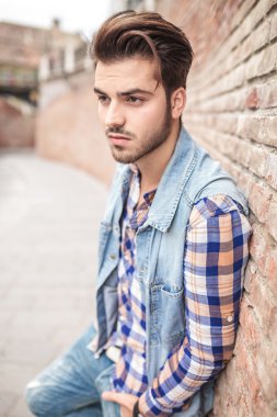 adam elini cebine, duvara yaslanmış