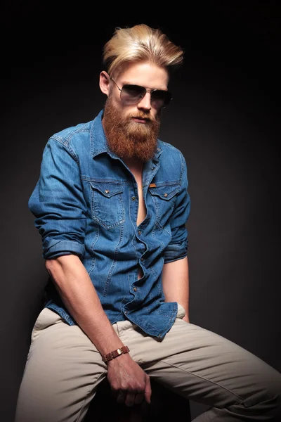 Hombre de moda en camisa azul y gafas de sol sentado — Foto de Stock