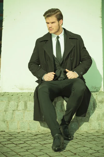 Elegant business man sitting on a sidewalk — Stock Photo, Image