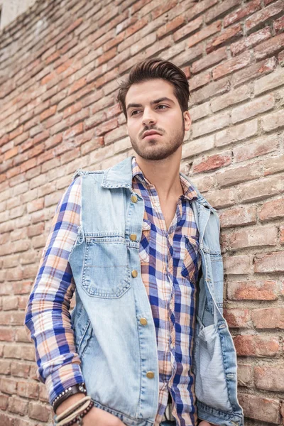 Joven hombre casual apoyado en una pared de ladrillo — Foto de Stock