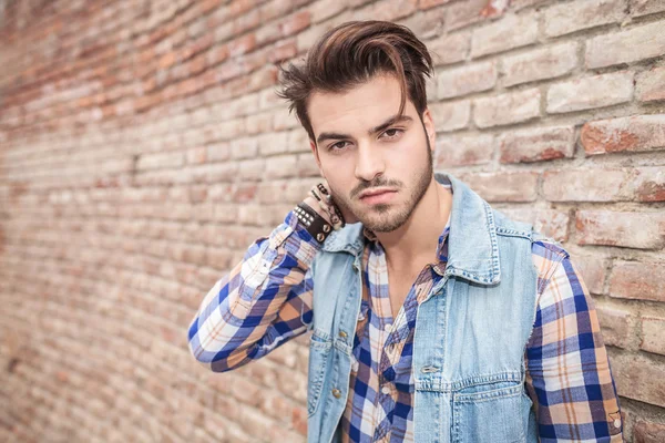 Man leaning on wall with one hand on his neck — Stock Photo, Image