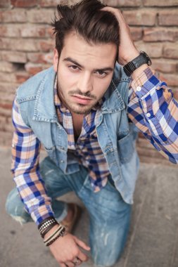 Saçında bir eliyle oturan adam