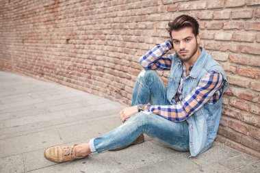 yakışıklı bir adam duvara yaslanmış kaldırımda dinlenme
