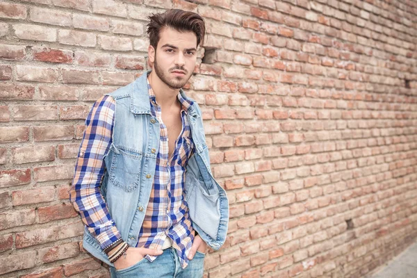 Homme les mains dans la poche, appuyé sur un mur — Photo