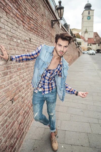 Hombre guapo apoyado en una pared de ladrillo, en la ciudad —  Fotos de Stock