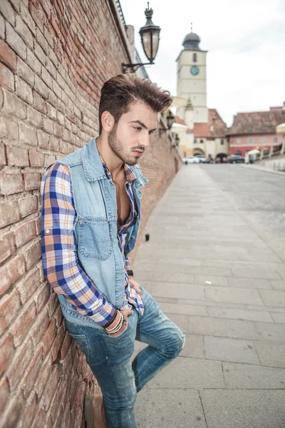 Jonge man leunend op een bakstenen muur — Stockfoto