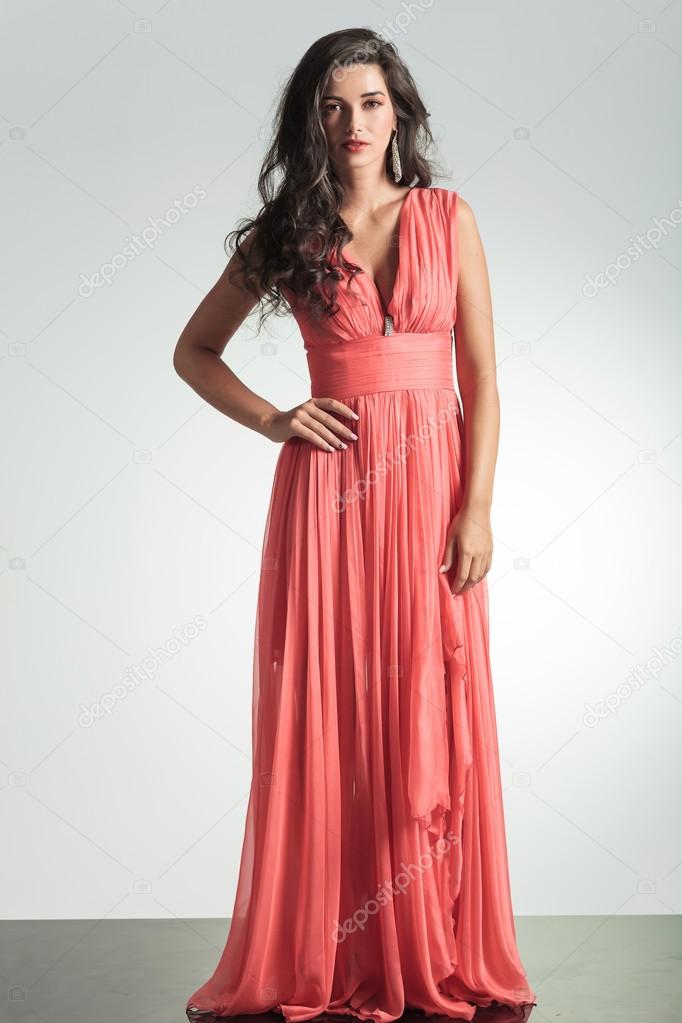 Elegant woman in red dress standing with hand on hip