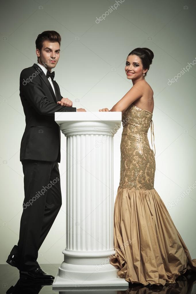 Happy elegant couple leaning ona column