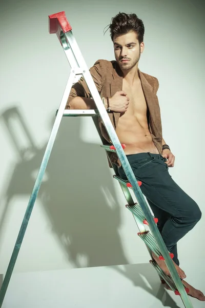 Homem de moda bonito inclinando-se para uma escada — Fotografia de Stock