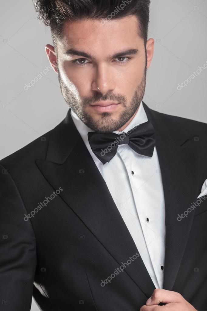 Handsome young man in tuxedo ajusting his jacket Stock Photo by