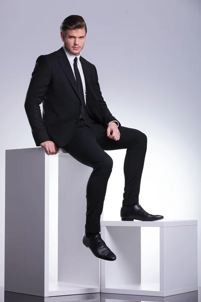 Młody biznes elegancki mężczyzna siedzi na stół biały — Zdjęcie stockowe