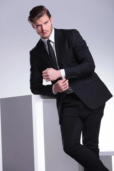 Elegant business man leaning on a white cube table — Stock Photo, Image