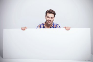 bir büyük beyaz pano tutarken gülümseyen moda erkek.