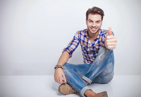 Jovem sorrindo enquanto mostra os polegares para cima gesto . — Fotografia de Stock