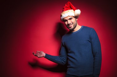Genç santa bir şey kırmızı bir duvar üzerinde sunulması
