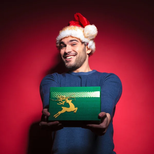 Handsome young santa giving you a green gift — Stock Photo, Image