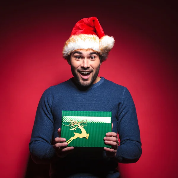 Happy young santa man holding a green gift. — Stock Photo, Image