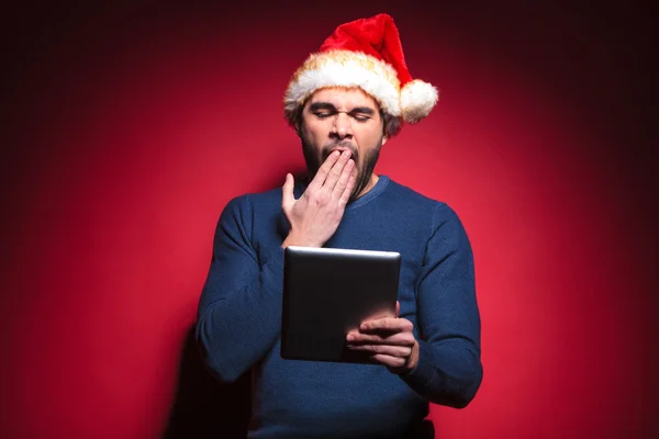 Tired santa man reading on a tablet pad computer — Stock Photo, Image