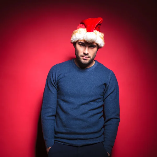 Young man wearing red santa hat holding hands in pockets — Stock Photo, Image