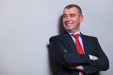 gri duvara yaslanmış orta yaşlı iş adamı