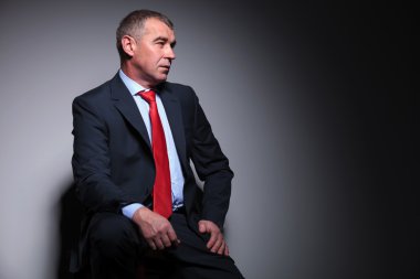 uzağa bakarken oturan orta yaşlı iş adamı