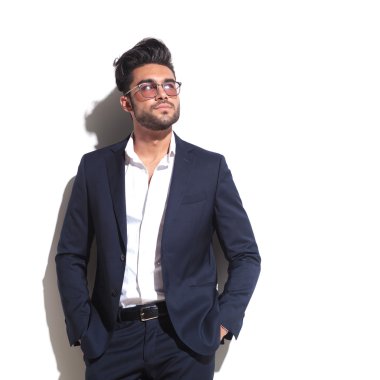 Beyaz duvara yaslanmış çekici iş adamı