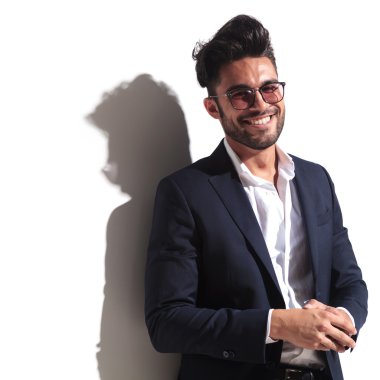  Beyaz duvara yaslanmış gülümseyen iş adamı