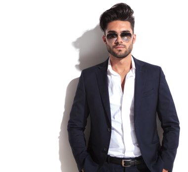 Beyaz duvara yaslanmış yakışıklı iş adamı